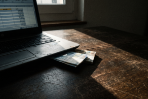 Nebeneinkommen aufbauen neben Job - Laptop mit Einnahmen-Tabelle und Franken-Noten